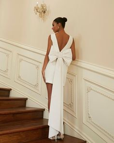 a woman in a white dress standing on some stairs with her back to the camera