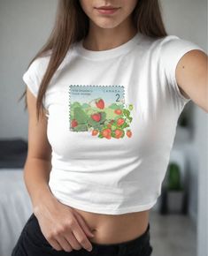 An instant classic, this baby tee captures the essence of summer sweetness.  Illustrated Strawberries on a Postage Stamp Bursting Forth into Reality on a shirt designed to be styled as a short and fitted top.  It's giving 90s and early 2000s baby tee. Refer to the size chart for to achieve your preferred fit.  This design is also available on a classic-fit unisex tee, a sweatshirt, and a  wristlet clutch. PRODUCT DETAILS .: Made with 100%, midweight (5.3 oz/yd² (180 g/m US cotton that feels soft to the touch and a great choice for any season. .: Fabric blends: Heather colors - 50% cotton, 50% polyester,  Sport Grey - 90% cotton, 10% polyester. .: Shirt is Gildan model 5000B, a classic, crew neck style .:Tear-away label for scratch-free wear .: Made using ethically grown and harvested US co Retro Spring Tops With Strawberry Print, Retro Spring Top With Strawberry Print, Vintage Fruit Print Crew Neck Tops, Vintage Crew Neck Tops With Fruit Print, Y2k Strawberry Print Short Sleeve Tops, Y2k Short Sleeve Tops With Strawberry Print, Retro Strawberry Print Summer Tops, Retro Strawberry Print Tops For Summer, Retro Cotton Top With Strawberry Print