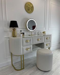 a white vanity with gold accents and a round mirror on the wall next to it