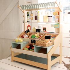 a wooden toy kitchen with food in the drawer and on the shelf next to it