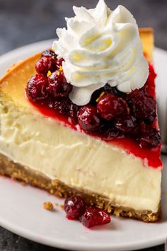 a piece of cheesecake on a plate with whipped cream and cherries