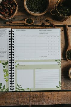 a recipe book sitting on top of a wooden table next to bowls and spoons