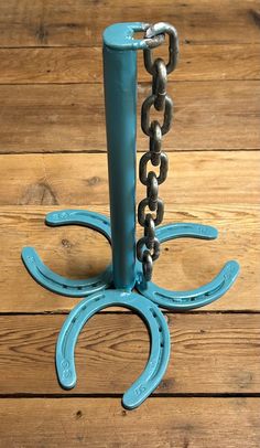 a blue metal hook with chains hanging from it's sides on a wooden floor