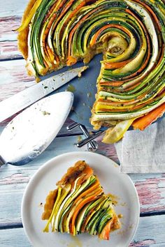 a slice of vegetable quiche on a white plate with a fork and knife next to it