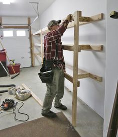 a man standing on top of a wooden ladder next to a wall filled with tools