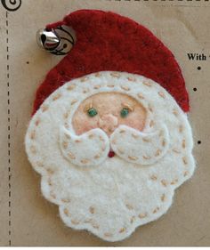 a close up of a santa clause ornament on a piece of paper with a bell