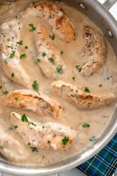 a pan filled with chicken and gravy on top of a blue checkered table cloth