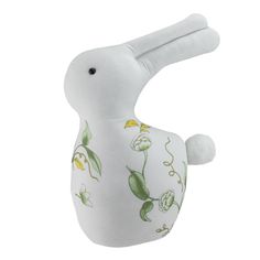 a white stuffed bird with green leaves and flowers on it's body, sitting in front of a white background