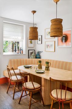 a dining room table with four chairs around it and pictures on the wall behind it