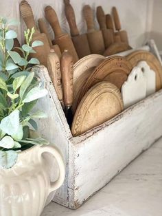 a white vase filled with lots of wooden utensils