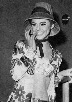 a woman talking on a cell phone while wearing a flowered shirt and hat with an attached neck tie