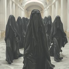 a group of women in black robes walking through a hallway with columns on either side