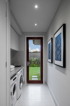 a washer and dryer sitting in a room next to a doorway with pictures on the wall