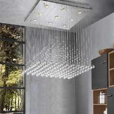 a modern chandelier hanging from the ceiling in a room with grey walls and flooring