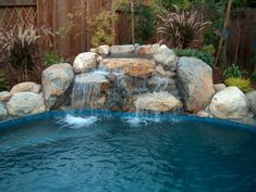 a pool with rocks and water features a waterfall