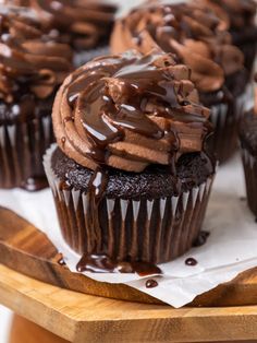 cupcakes with chocolate frosting and drizzled on top sitting on a cutting board