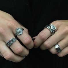 two hands with rings on their fingers, one is wearing a black shirt and the other has