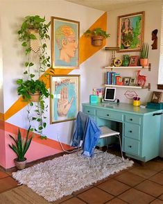 a room with a desk, potted plant and pictures on the wall