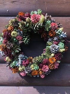 a wreath made out of pine cones and succulents on a wooden wall