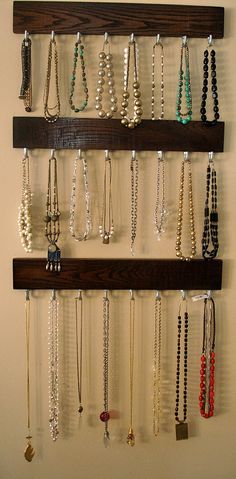 a wall mounted jewelry rack with several necklaces hanging on it's wooden shelves