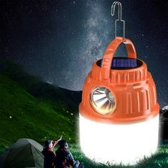 an orange lantern is sitting in the grass with two people around it and stars above