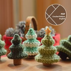 small crocheted christmas trees sitting on top of a wooden table next to pine cones