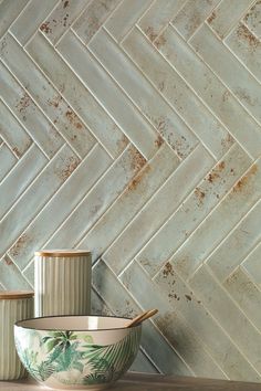 two ceramic bowls sitting next to each other on a wooden table in front of a tiled wall