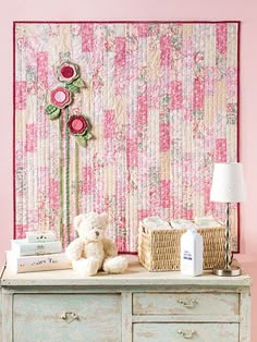 an old dresser with a teddy bear and flowers on the top, next to a pink wallpaper