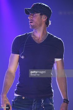 the singer performs on stage at an event in front of purple lights, wearing headphones and