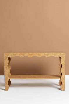 a wooden bench with scalloped edges against a brown wall