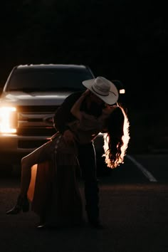 a man and woman kissing in front of a truck on the side of the road