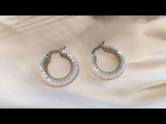 two pairs of earrings sitting on top of a white cloth