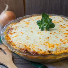 a casserole dish with cheese and herbs on top