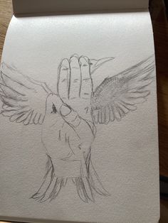 a drawing of a hand holding a bird with its wings spread out, on top of a piece of paper