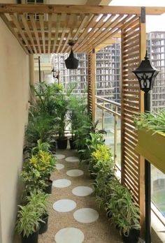 a long walkway with potted plants and lights on either side of the walkway is covered by wood slats