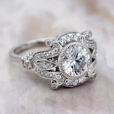 a close up view of a diamond ring on a white cloth with the center stone surrounded by diamonds