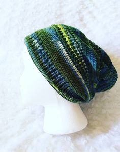 a white mannequin head wearing a green and blue knitted beanie hat