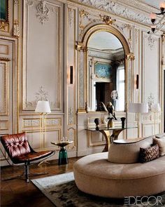 a living room filled with lots of furniture next to a mirror and chandelier