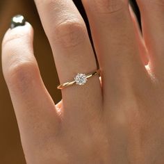 a woman's hand with a diamond ring on top of her finger, showing the center stone