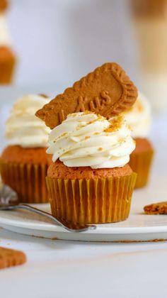 two cupcakes with frosting and cookie decorations on top are sitting on a plate