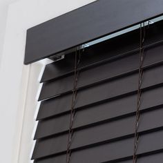 a close up of a window with black blinds and chains hanging from it's side