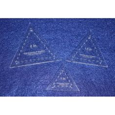 three clear triangle shaped glass coasters sitting on top of a blue cloth covered table