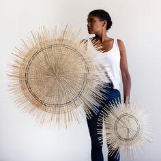 a woman is holding two large woven objects