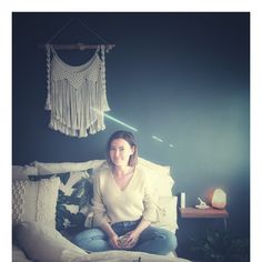 a woman sitting on top of a bed next to a string hanging from the ceiling