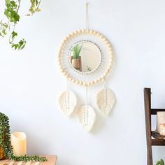 a mirror hanging on the wall next to a table with candles and plants in it