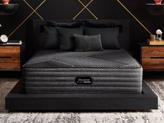 a black bed with two pillows on top of it next to a night stand and nightstands