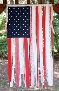 an american flag hanging from a tree with white lace and black polka dots on it