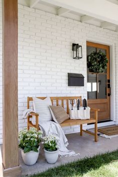 a wooden bench sitting on top of a porch next to a planter filled with flowers