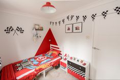 a child's bedroom decorated in red, white and black with race themed decor