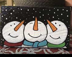 a painting of three snowmen with carrots on their heads